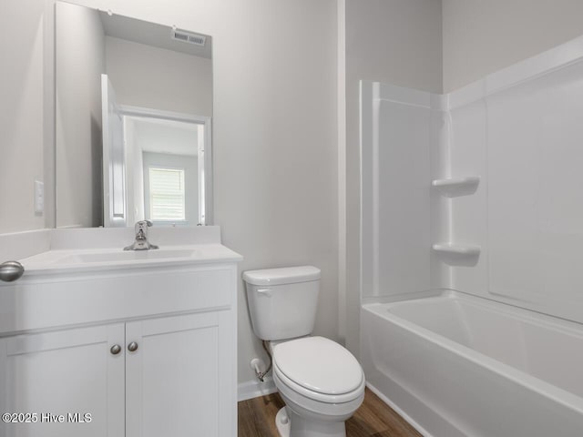 bathroom featuring toilet, wood finished floors, vanity, baseboards, and shower / tub combination