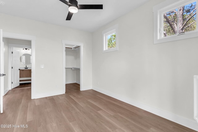 808 S 2nd St, Carolina Beach, NC 28428 - unfurnished bedroom with wood finished floors, baseboards, a walk in closet, a closet, and a ceiling fan