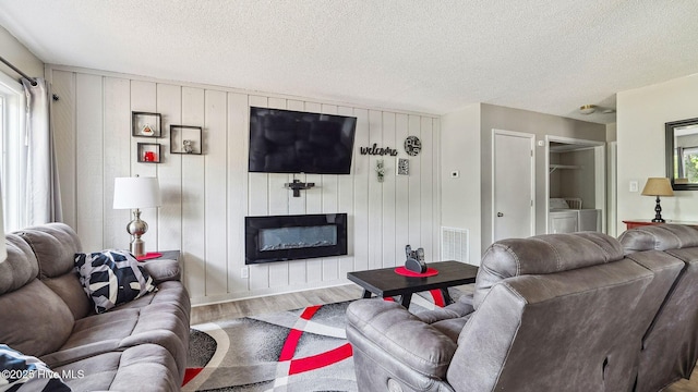 227 Foxkroft Dr Unit 9, Foxfire Village, NC 27281 - living area featuring wood finished floors, washer and dryer, a glass covered fireplace, healthy amount of natural light, and a textured ceiling