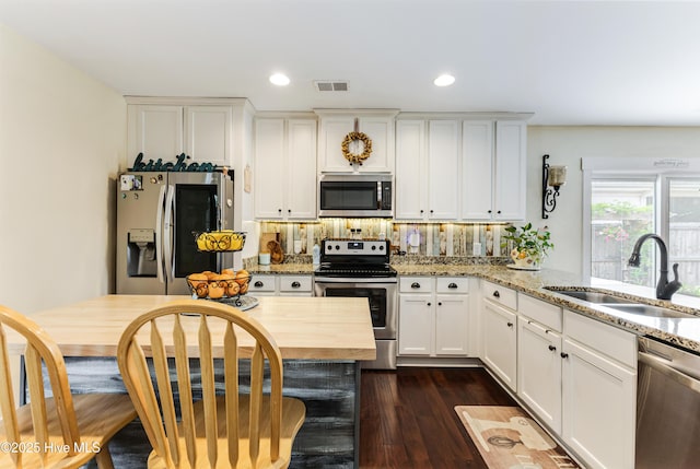 131 NE 33rd St, Oak Island, NC 28465 - kitchen featuring appliances with stainless steel finishes, a sink, white cabinetry, light stone countertops, and recessed lighting