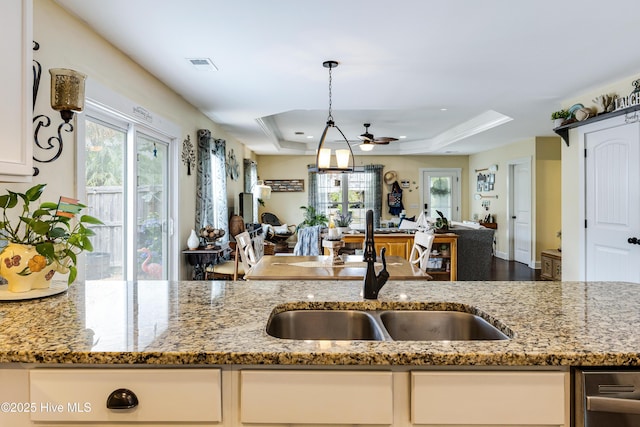 131 NE 33rd St, Oak Island, NC 28465 - kitchen featuring open floor plan, a sink, a raised ceiling, and light stone counters