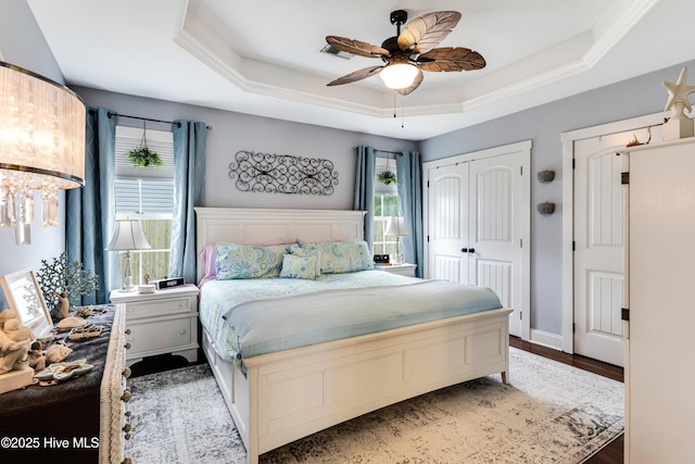 131 NE 33rd St, Oak Island, NC 28465 - bedroom featuring a tray ceiling, wood finished floors, a closet, and a ceiling fan