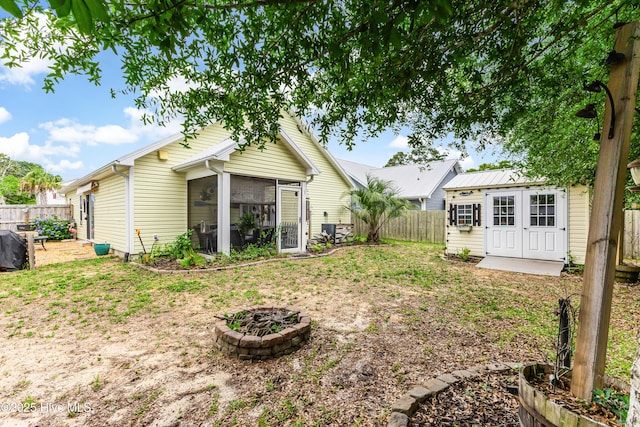 131 NE 33rd St, Oak Island, NC 28465 - back of house with a fenced backyard, a sunroom, and an outdoor structure