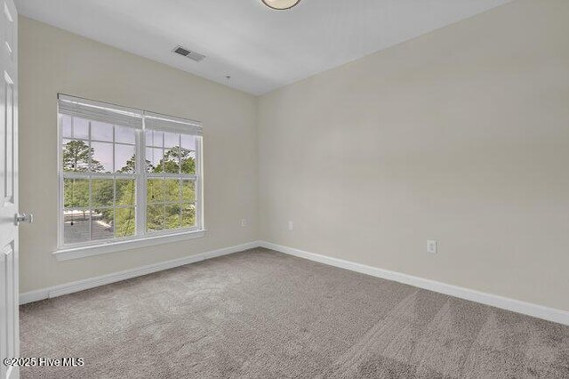 carpeted empty room featuring baseboards