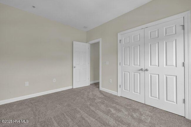 unfurnished bedroom with carpet floors, baseboards, and a closet