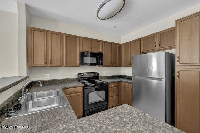 kitchen featuring black appliances, a sink, dark countertops, brown cabinets, and a peninsula