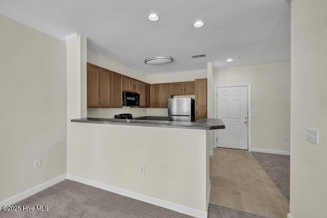 kitchen featuring black microwave, freestanding refrigerator, light colored carpet, baseboards, and dark countertops