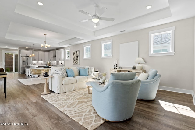 living room with a tray ceiling, a chandelier, ceiling fan, wood finished floors, and recessed lighting