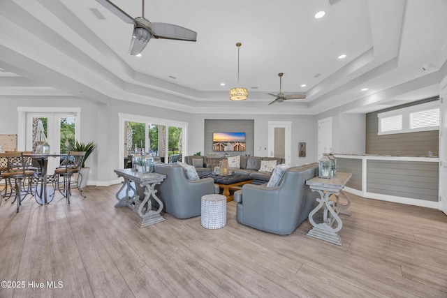 living room with ceiling fan, a tray ceiling, french doors, recessed lighting, and wood finished floors