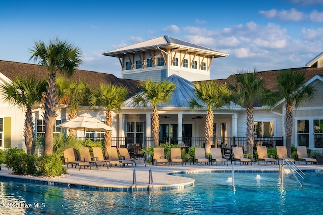 back of property featuring fence, a community pool, ceiling fan, a patio area, and metal roof