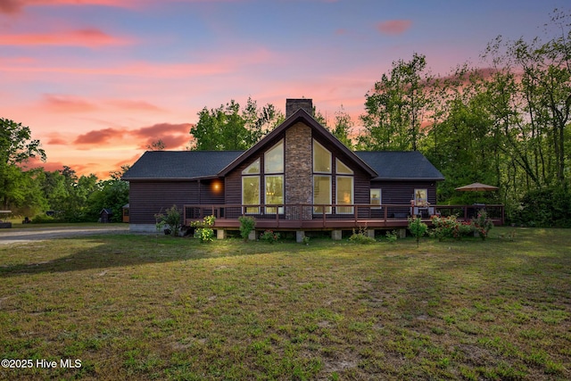 181 Kirkpatrick Ln, Red Springs, NC 28377 - back of house at dusk featuring a wooden deck, a chimney, a lawn, and stone siding