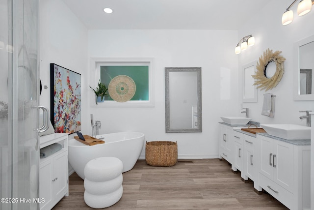 181 Kirkpatrick Ln, Red Springs, NC 28377 - bathroom with wood finished floors, double vanity, a soaking tub, baseboards, and recessed lighting