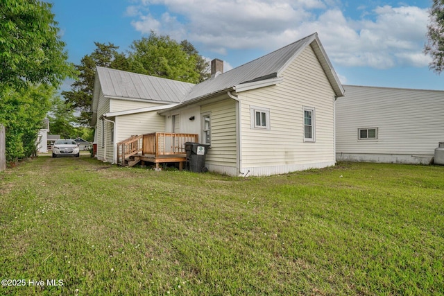 rear view of property featuring metal roof, a yard, and a chimney