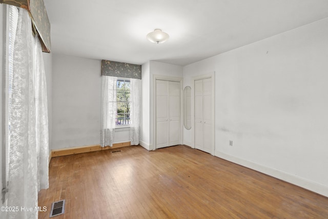 306 S Oakum St, Edenton, NC 27932 - unfurnished bedroom with hardwood / wood-style flooring, baseboards, and two closets