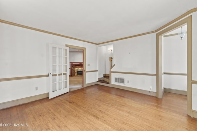 306 S Oakum St, Edenton, NC 27932 - empty room featuring light wood-style flooring, ornamental molding, stairs, a brick fireplace, and baseboards