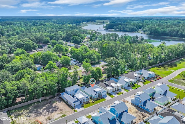 aerial perspective of suburban area with a large body of water and a heavily wooded area