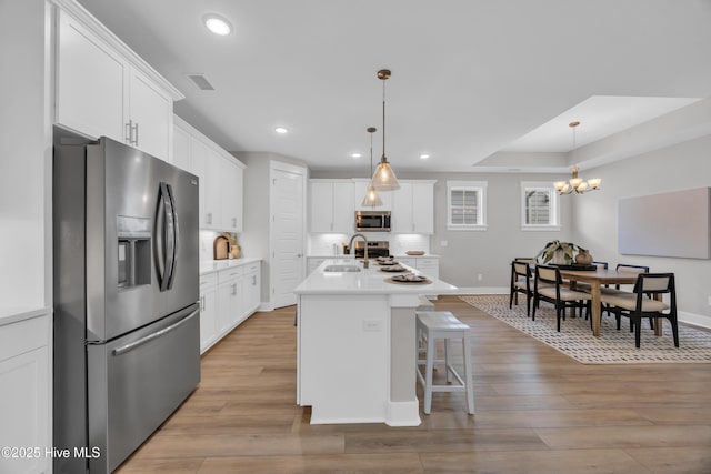 kitchen featuring appliances with stainless steel finishes, a sink, light wood-style flooring, white cabinets, and recessed lighting