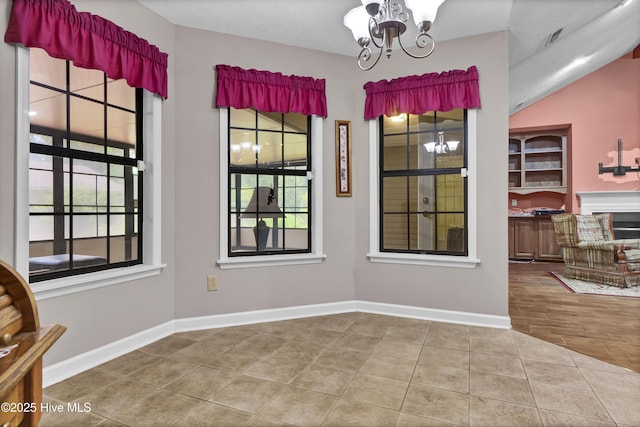 unfurnished dining area with plenty of natural light, a chandelier, tile patterned flooring, and baseboards