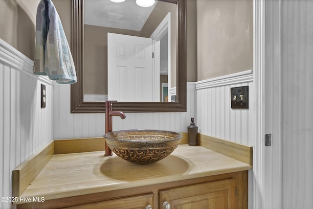 bathroom with a wainscoted wall, vanity, and a decorative wall