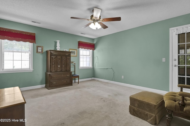 sitting room with a ceiling fan, a textured ceiling, baseboards, and carpet