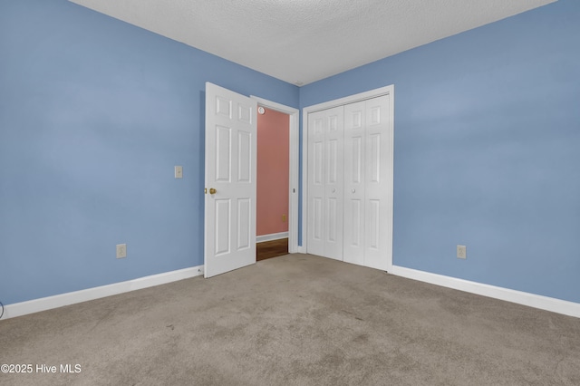 unfurnished bedroom with baseboards, a closet, carpet floors, and a textured ceiling