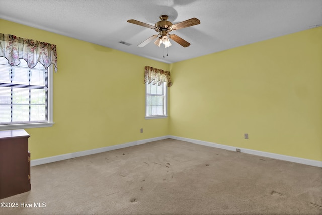 carpeted spare room featuring ceiling fan and baseboards