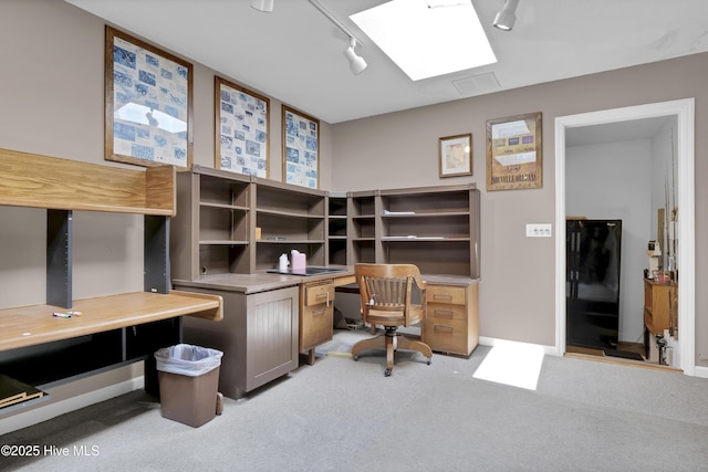 office space with light carpet, built in desk, track lighting, and a skylight