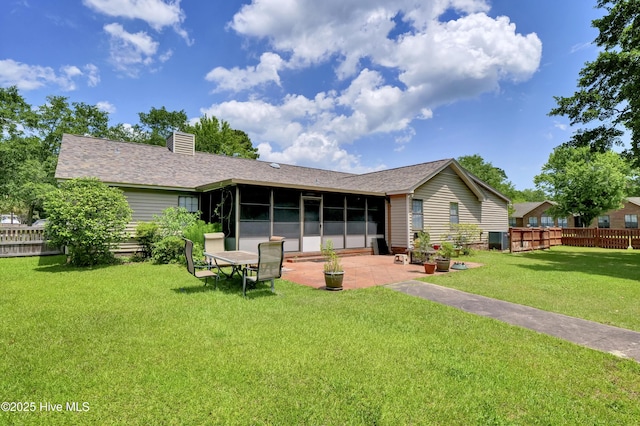 back of house featuring a sunroom, a chimney, a patio area, and roof with shingles