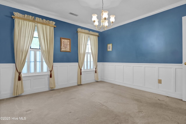 spare room with a chandelier, a wainscoted wall, a decorative wall, crown molding, and carpet