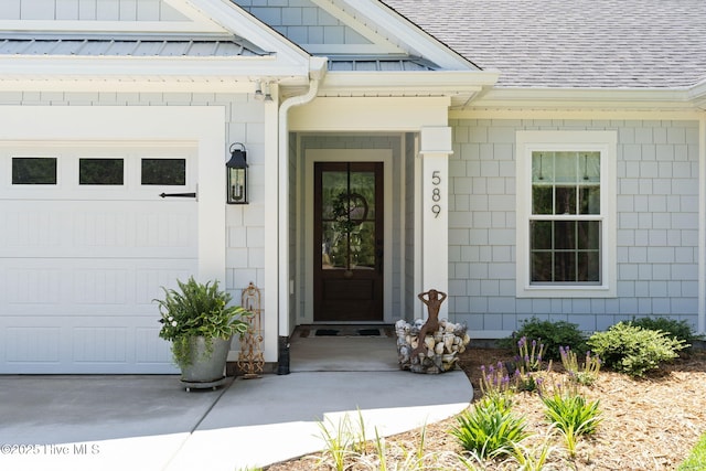 doorway to property with a shingled roof and an attached garage