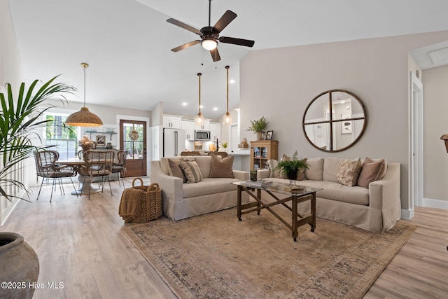 living area with a ceiling fan, light wood-style flooring, high vaulted ceiling, and baseboards