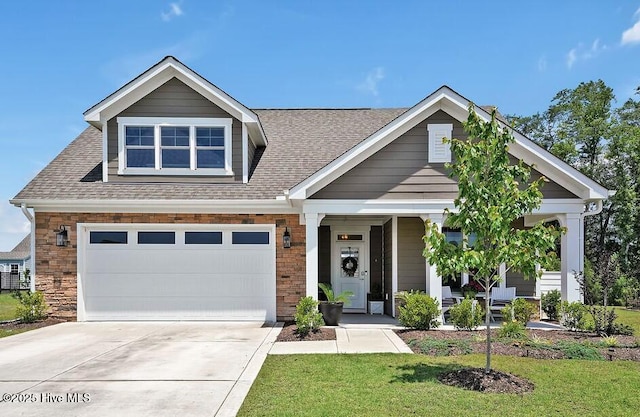 craftsman-style home with concrete driveway, a porch, a shingled roof, and a front yard