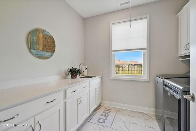 washroom with cabinet space, separate washer and dryer, light marble finish floors, and baseboards