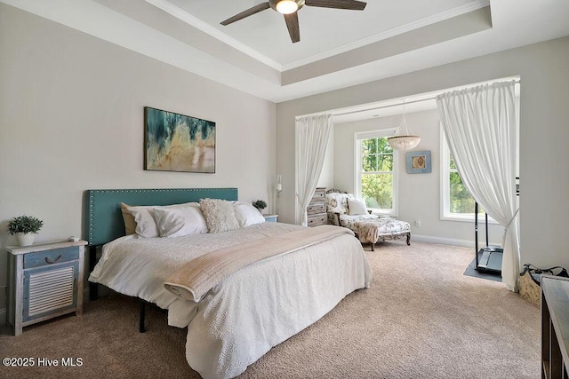 bedroom featuring carpet, a tray ceiling, crown molding, baseboards, and a ceiling fan