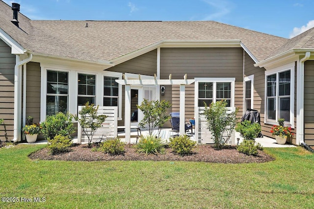 entrance to property featuring a lawn, roof with shingles, a patio area, and a pergola