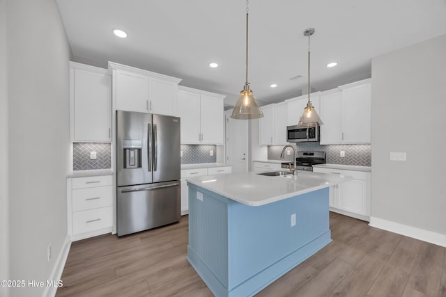 kitchen featuring stainless steel appliances, light wood finished floors, a sink, light countertops, and recessed lighting