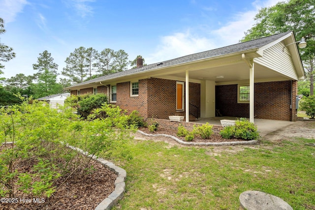 view of property exterior featuring brick siding, a chimney, a carport, and a lawn