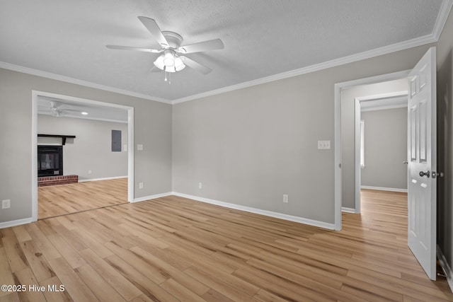 unfurnished living room featuring ceiling fan, light wood-style floors, baseboards, ornamental molding, and a fireplace
