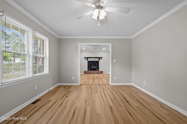 unfurnished living room featuring ceiling fan, a fireplace, light wood-style flooring, baseboards, and crown molding