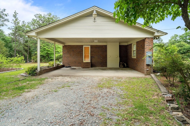 view of front of house featuring gravel driveway, brick siding, and a front yard