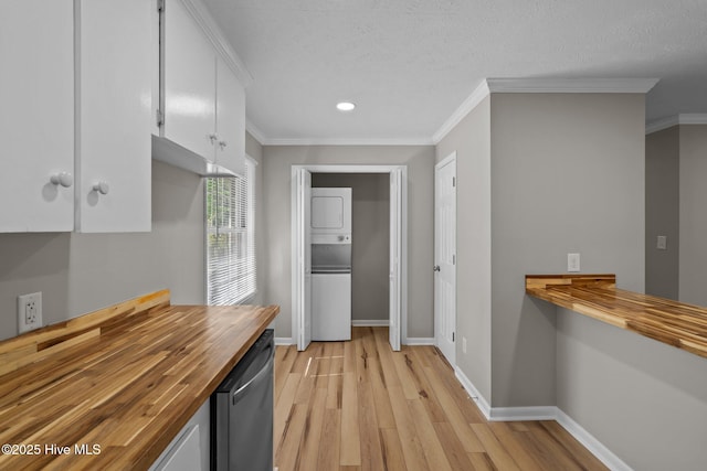 kitchen with wood counters, stacked washer / dryer, light wood-style floors, white cabinetry, and ornamental molding