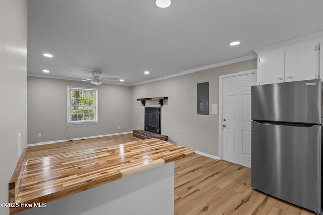 unfurnished living room with electric panel, a ceiling fan, recessed lighting, a glass covered fireplace, and light wood-style flooring