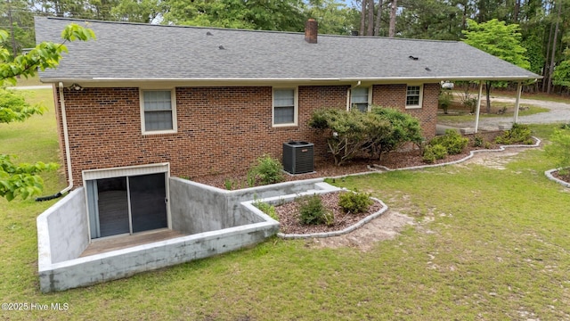 rear view of property with a yard, brick siding, roof with shingles, and central AC unit