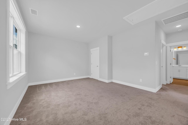 carpeted empty room featuring attic access, baseboards, and recessed lighting