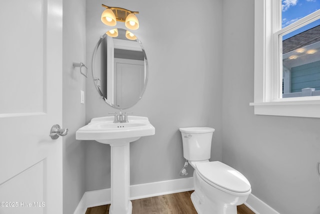 bathroom with baseboards, toilet, and wood finished floors