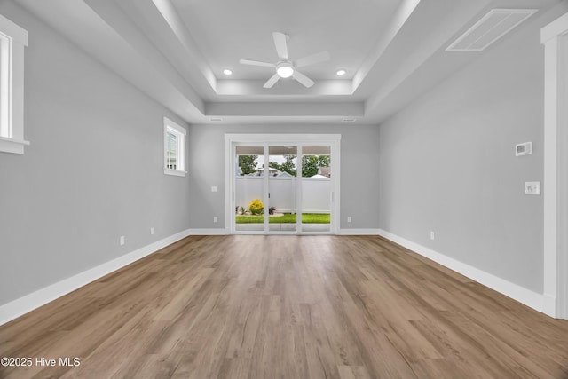 unfurnished room with a ceiling fan, light wood-type flooring, baseboards, a raised ceiling, and recessed lighting