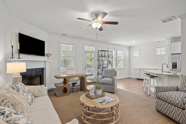 160 Freedom Park Rd, Beaufort, NC 28516 - living room with a fireplace, a ceiling fan, crown molding, light wood-style floors, and baseboards