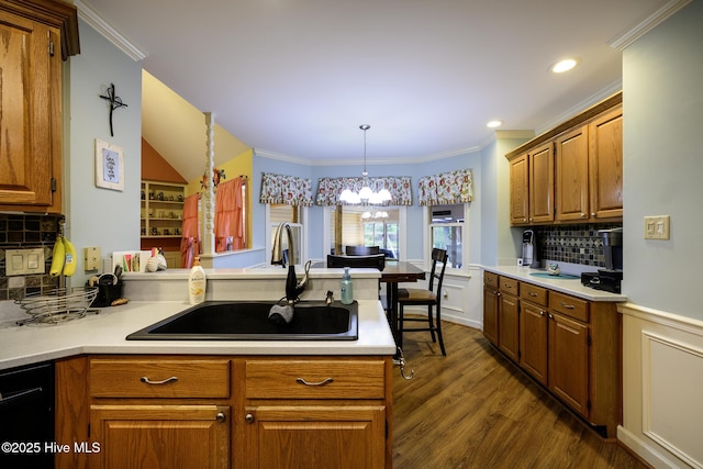 1992 Acorn Dr, New Bern, NC 28562 - kitchen with a chandelier, a peninsula, brown cabinets, tasteful backsplash, and light countertops