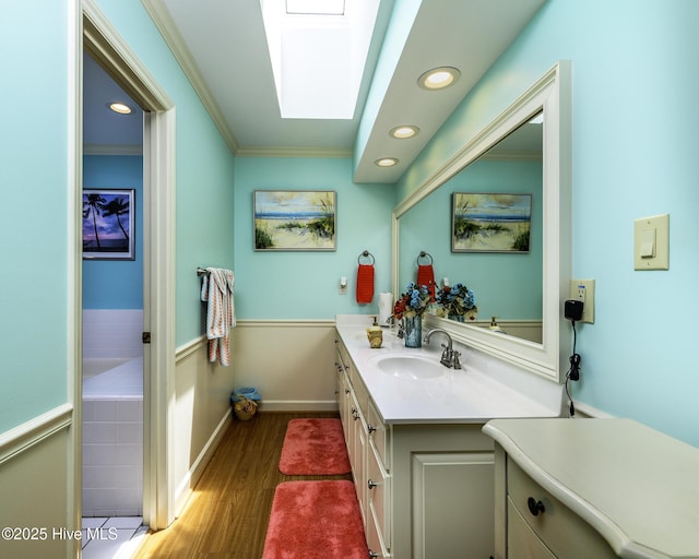 1992 Acorn Dr, New Bern, NC 28562 - bathroom featuring wood finished floors, vanity, ornamental molding, a tub, and a skylight