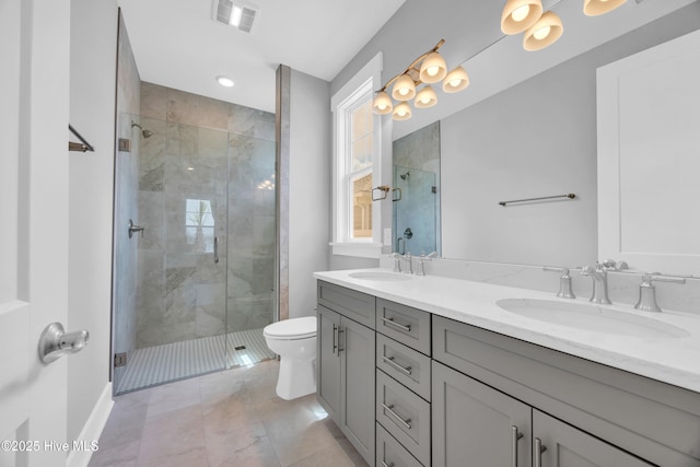 full bath featuring toilet, a shower stall, double vanity, and baseboards